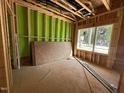 Unfinished bedroom featuring stud framing, exterior sheathing, and window overlooking the neighborhood at 1523 Sunrise Ave, Raleigh, NC 27608