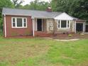 Charming one-story home featuring a brick facade, stone accents, and a lush green lawn at 1610 W B St, Butner, NC 27509