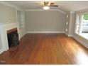 Living room featuring a fireplace, built-in shelves, ceiling fan, and hardwood floors at 1610 W B St, Butner, NC 27509