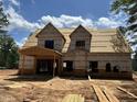 The front of a home under construction shows an open garage and dormers on the second story surrounded by a large yard at 194 Landon Ridge, Sanford, NC 27330