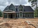 New construction home featuring a green exterior, black roof, and spacious covered porch at 194 Landon Ridge, Sanford, NC 27330