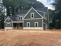 Green two-story home with white trim, black roof, and attached garage in a wooded setting at 194 Landon Ridge, Sanford, NC 27330