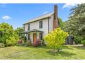 Charming two-story home featuring a metal roof, brick chimney, and beautifully landscaped yard at 2440 Glencoe St, Burlington, NC 27217