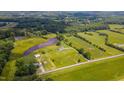 Expansive aerial view showcases the home's picturesque setting amidst green fields and a tranquil pond at 2912 Epps Clark Rd, Siler City, NC 27344