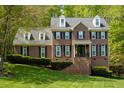 Traditional brick home with well-manicured lawn, dormer windows, and lush surrounding greenery at 5025 Martin Farm Rd, Raleigh, NC 27613