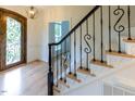 Inviting foyer with hardwood floors, decorative wrought iron staircase, and view of the front door at 5025 Martin Farm Rd, Raleigh, NC 27613