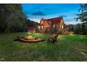 Spacious backyard featuring a fire pit, Adirondack chairs, and a charming log home surrounded by trees at 6707 Frieden Church Rd, Gibsonville, NC 27249