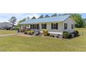Landscaped front yard showing the home's exterior, featuring a metal roof, manicured lawn and walkway at 8163 Julian Rd, Dunn, NC 28334