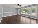 Well-lit living room featuring laminate flooring, a ceiling fan, and a large bright window at 8163 Julian Rd, Dunn, NC 28334