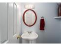 Elegant powder room featuring an oval mirror, pedestal sink, and decorative light fixture at 8908 Shallcross Way, Raleigh, NC 27617