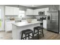 Modern kitchen with white cabinets, stainless steel appliances, granite countertops, and a large island with seating at 117 N Coral Bells Way, Four Oaks, NC 27524