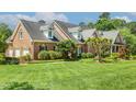 Side angle of a brick house featuring a well-maintained lawn and a classic architectural design at 129 Trellingwood Dr, Morrisville, NC 27560