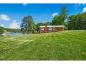 Picturesque view of a brick home with a lush green lawn and lake access, offering a serene and inviting outdoor space at 1415 Clearwater Dr, Sanford, NC 27330