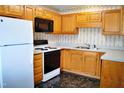 Efficient kitchen with wooden cabinets, white appliances, and black and white linoleum flooring at 3027 Maple Ave # Apt K3, Burlington, NC 27215