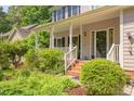 Inviting front porch with brick steps, white railings, and lush landscaping, offering curb appeal at 401 Robert Hunt Dr, Carrboro, NC 27510