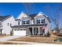 Charming two-story home featuring a stone-accented garage, gray siding, and an inviting front porch with an American flag at 416 Longleaf Glen Ln, Zebulon, NC 27597
