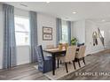 Sunlit dining area with stylish wood table, chairs, modern decor, and natural light from the bright windows at 420 Longleaf Glen Ln, Zebulon, NC 27597