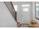 Bright entryway featuring hardwood floors, stairs with a dark wood banister, and a white front door at 420 Longleaf Glen Ln, Zebulon, NC 27597
