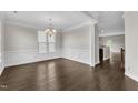 Bright dining room with hardwood floors, classic trim, and stylish chandelier; open floor plan view to kitchen at 1001 Tender Dr, Apex, NC 27502