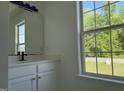 Bathroom featuring white cabinets, a modern mirror, and a large window at 118 Hawthorn Dr, Clayton, NC 27520