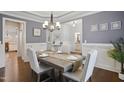 Elegant dining room featuring gray walls, wainscoting, a tray ceiling, and a chandelier at 1212 Sand Pine Dr, Cary, NC 27519