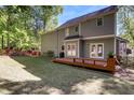 View of the backyard featuring a wooden deck, lush green lawn, and mature trees at 141 Clay Ridge Way, Holly Springs, NC 27540
