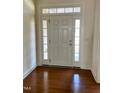 Inviting entryway featuring a white front door, sidelights, transom window and wood floors at 1549 Lily Creek Dr, Cary, NC 27518