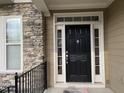 Close up of front door with black door, transom window and stone accents at 1549 Lily Creek Dr, Cary, NC 27518