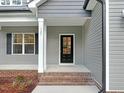 Welcoming front entry with black door, brick steps, gray siding and white trim at 157 Gumtop Dr, Zebulon, NC 27597