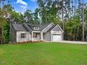 Beautiful single-story home showcases gray siding, black shutters, and lush green lawn surrounded by mature trees at 157 Gumtop Dr, Zebulon, NC 27597