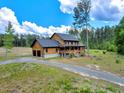 Aerial view of a two-story log home with an attached garage, and long driveway surrounded by lush greenery at 2092 Winwood Farm Rd, Creedmoor, NC 27522