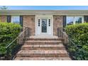 Close up of the front door featuring brick steps, black railings and mature landscaping at 2606 Newquay St, Durham, NC 27705
