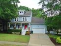 Charming two-story home with a red front door, covered porch, lush landscaping, and an attached two-car garage at 3300 Neuse Crossing Dr, Raleigh, NC 27616