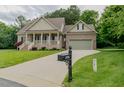View of driveway leading to brick home with manicured front lawn, shrubs and mailbox at 4667 Freedom Dr, Burlington, NC 27215