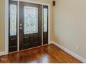 Elegant front door with decorative glass panes and dark wood trim and gleaming hardwood floors at 4667 Freedom Dr, Burlington, NC 27215