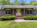 Inviting brick home featuring a covered front porch with decorative ironwork and well-maintained landscaping at 5529 Shadowbrook Dr, Raleigh, NC 27612