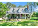Charming home featuring a welcoming front porch, dormer windows, and manicured lawn and beautiful landscaping at 100 Mill Creek Dr, Fuquay Varina, NC 27526