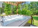 Outdoor hot tub with surrounding wooden deck, privacy fence, and backyard trees at 100 Mill Creek Dr, Fuquay Varina, NC 27526