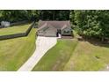 An aerial view of a quaint single-story home with a three-car garage and spacious yard surrounded by lush trees at 123 Terawood Farm Dr, Willow Springs, NC 27592