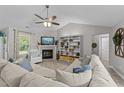 Bright living room features a fireplace, vaulted ceilings with ceiling fan, and a large sectional sofa at 123 Terawood Farm Dr, Willow Springs, NC 27592
