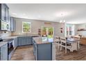 An open-concept kitchen featuring blue cabinets, a granite island, stainless steel appliances, and an adjacent dining area at 45 Iris Dr, Youngsville, NC 27596