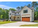 Wide view of the house and driveway featuring modern design elements with a wood-toned garage door at 1301 Doylin Dr, Cary, NC 27511