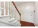 Traditional staircase with white spindles and a dark wood banister next to a white door at 1324 Swallow Dr, Raleigh, NC 27606