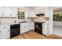 Bright kitchen with white cabinets, black appliances, light countertops, wood floors and natural light from the window at 1604 Westbridge Ct, Raleigh, NC 27606