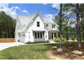 Beautiful white farmhouse-style home with a lush green lawn and natural wooded surroundings at 2200 Mays Crossroads Rd, Louisburg, NC 27549