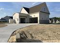 Spacious three-car garage with concrete driveway and stone accents on an attractive new construction home at 25 Deer Tail Ln # 52, Fuquay Varina, NC 27526