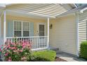 Inviting porch with white railing, light blue shutters, flowers, and a glimpse of a cozy spot to relax at 6904 Fox Haven Pl, Raleigh, NC 27616