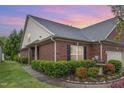 Charming brick home featuring manicured landscaping, green lawn, black shutters, and a delightful water fountain at 8005 Crookneck Dr, Angier, NC 27501
