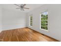 Bright bedroom features hardwood floors, two large windows, and modern ceiling fan at 809 Parkridge Dr, Clayton, NC 27527