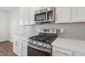 Shows the stainless steel range, microwave, white cabinets, and tile backsplash at 919 Montague Ave, Durham, NC 27703